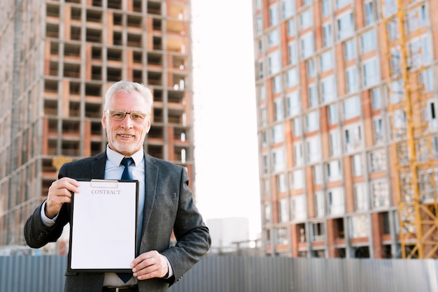 Vue de face vieil homme en costume tenant contrat