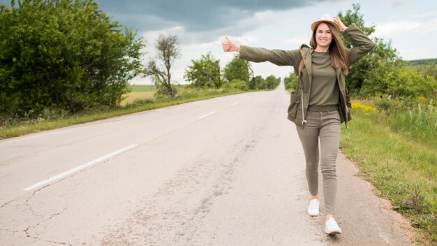 Vue de face voyageur élégant faisant de l'auto-stop