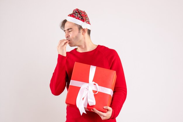 Vue de face yeux fermés jeune homme avec bonnet de Noel debout sur fond blanc