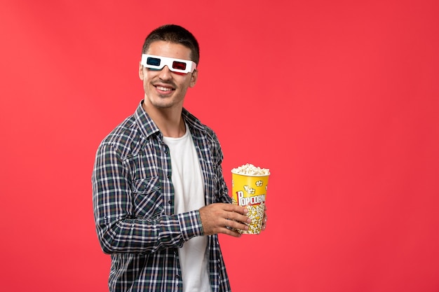 Vue De Face Young Male Holding Pop-corn En -d Lunettes De Soleil Sur Le Mur Rouge Cinéma Cinéma Film Cinéma