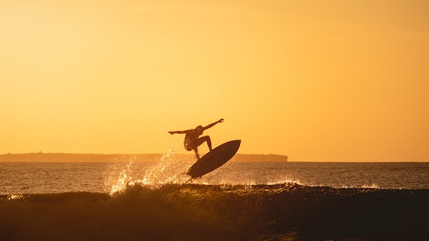 Vue fascinante de la silhouette d'un surfeur dans l'océan pendant le coucher du soleil en Indonésie