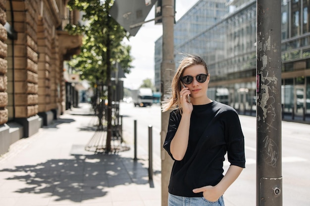 Vue d'une femme charmante regarde la caméra et tient un téléphone portable