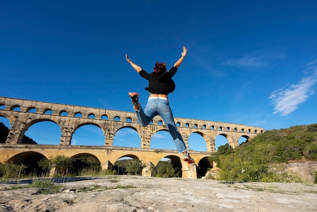 Vue de femme sautant devant le Pont du Gard