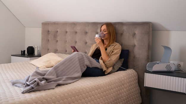 Photo gratuite vue d'une femme utilisant un nébuliseur à la maison pour des problèmes de santé respiratoire