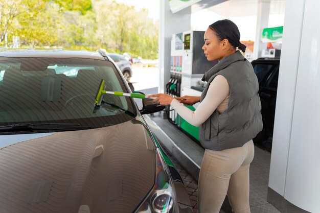 Vue de femme avec voiture à la station-service