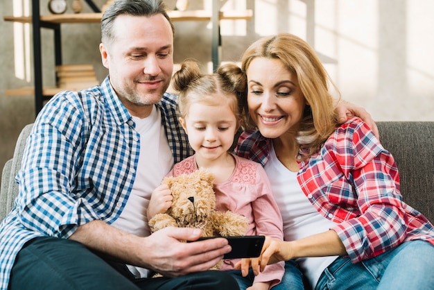 Vue frontale, de, famille heureuse, regarder, dans, téléphone portable