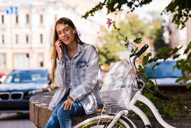 Vue frontale, femme, parler, téléphone, côté, vélo