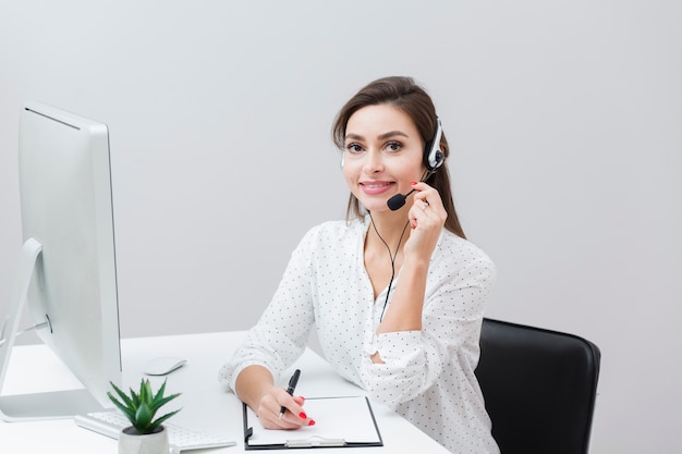 Vue frontale, de, femme souriante, poser, à, casque à écouteurs, bureau