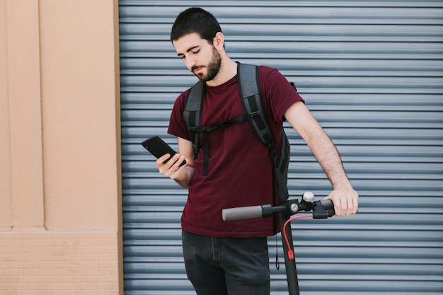 Vue frontale, homme tenant téléphone, sur, e-scooter