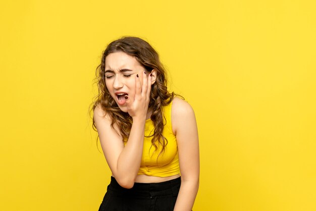 Vue frontale, de, jeune femme, avoir mal de dents, sur, mur jaune