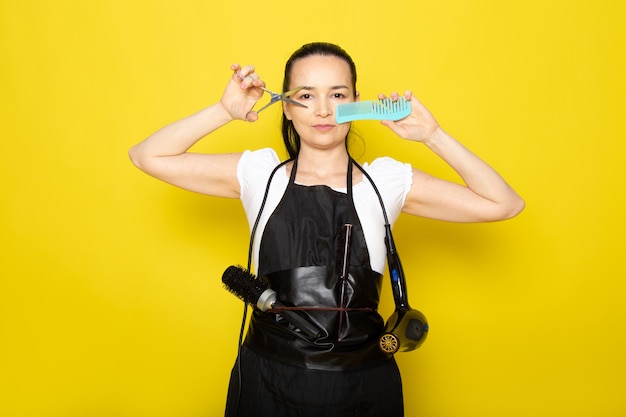 A, vue frontale, jeune, femme, coiffeur, dans, t-shirt blanc, cape noire, tenue, ciseaux, brosse, poser