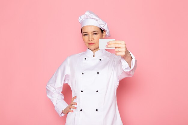 A, vue frontale, jeune femme, cuisinier, dans, cuisinier blanc, complet, blanc, casquette, poser, tenue, carte blanche