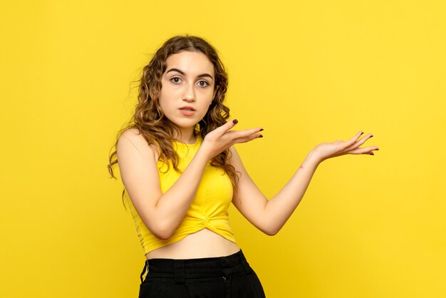 Vue frontale, de, jeune femme, debout, sur, mur jaune