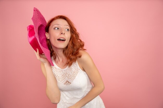 Vue frontale, de, jeune femme, poser, à, chapeau rose, sur, mur rose