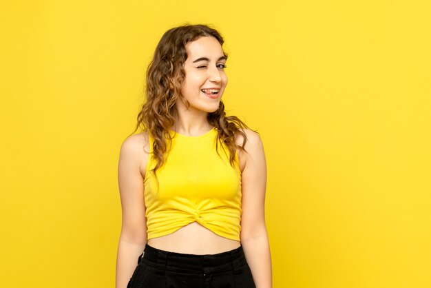 Vue frontale, de, jeune femme, sourire, et, clignotant, sur, mur jaune