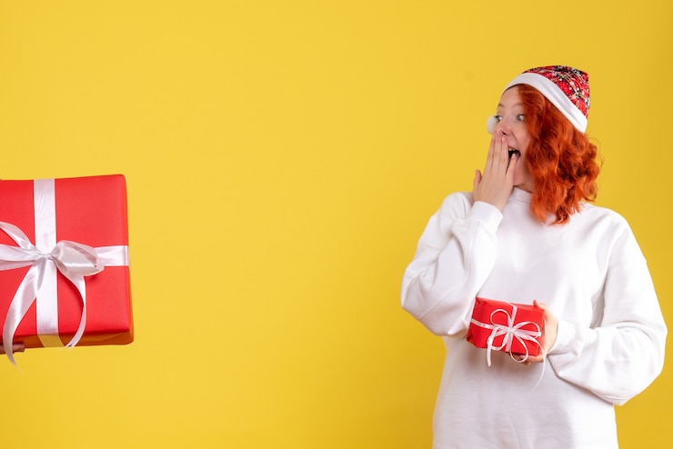 Photo gratuit vue frontale, de, jeune femme, tenue, peu, noël, présent, sur, mur jaune