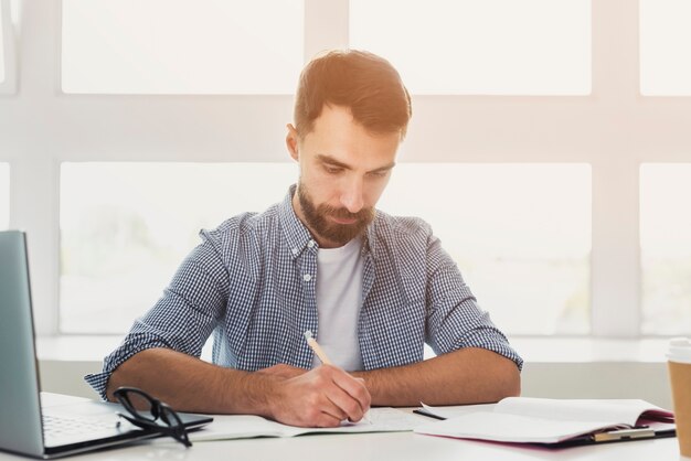 Vue frontale, jeune homme, bureau, écriture