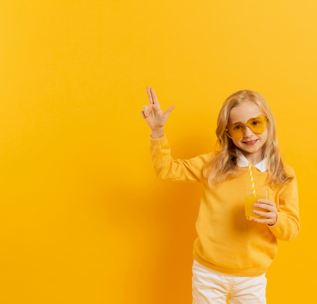 Photo gratuite vue frontale, de, smiley, girl, poser, quoique, porter lunettes soleil, et, tenue, verre jus