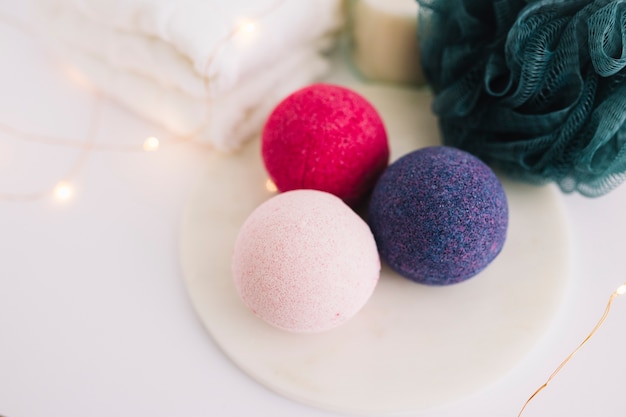 Vue grand angle des bombes de bain; luffa; serviette et guirlandes lumineuses sur une surface blanche