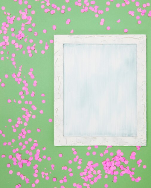 Vue grand angle de cadre vide avec des confettis roses sur fond vert