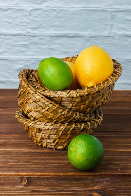 Photo gratuite vue grand angle de citrons dans des paniers sur une surface en bois. espace vertical pour le texte