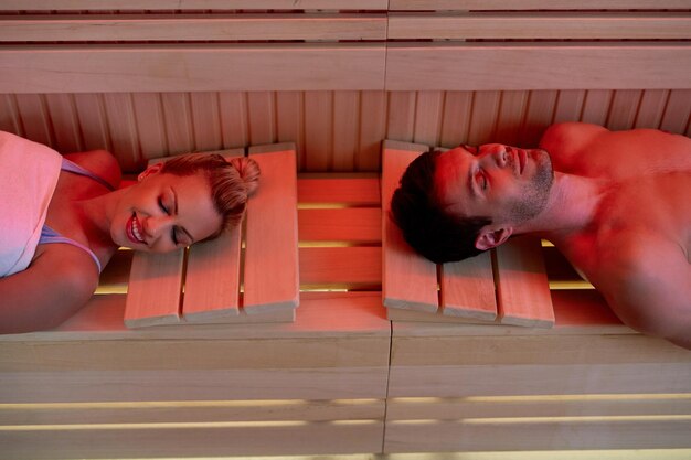 Vue grand angle d'un couple se relaxant les yeux fermés tout en étant dans un sauna au spa de santé