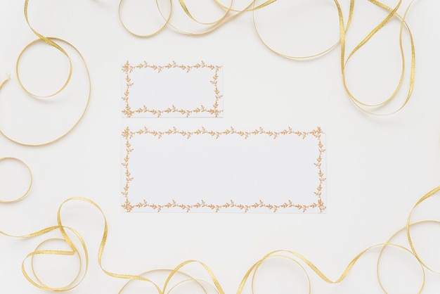 Vue grand angle de deux cartes vierges entourées de rubans sur une surface blanche