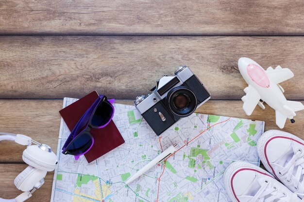 Vue grand angle de l&#39;écouteur; passeport; des lunettes de soleil; carte; stylo; caméra; chaussures et avion sur toile de fond en bois
