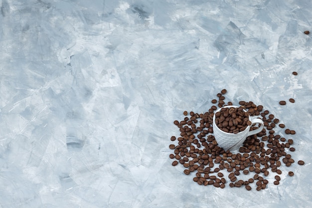 Photo gratuite vue grand angle des grains de café dans une tasse blanche sur fond de plâtre gris. horizontal