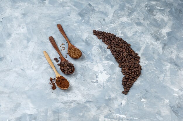 Vue grand angle de grains de café avec grains de café, café instantané, farine de café dans des cuillères en bois sur fond de marbre bleu clair. horizontal
