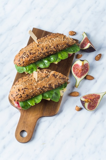 Vue grand angle de hot dogs frais sur une planche de bois près de figue et d&#39;amandes