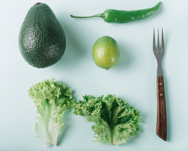 Vue grand angle de légumes verts frais avec une fourchette sur une surface verte