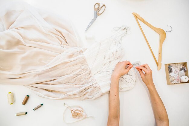 Vue grand angle de la main d&#39;un créateur de mode travaillant sur la robe sur fond blanc