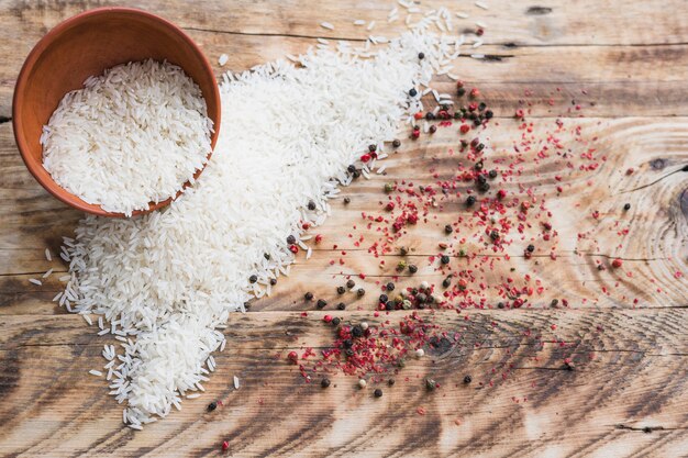 Vue grand angle de riz biologique dans un bol et de poivrons noirs aux épices sur papier peint en bois