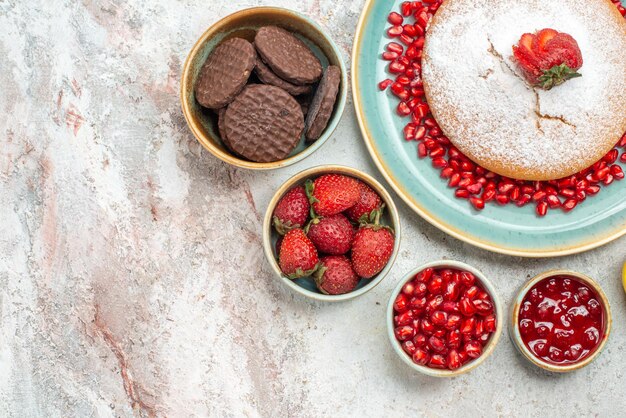 Vue en gros plan de dessus biscuits gâteau de fraises et bols de grenade de différents biscuits aux baies sur la table