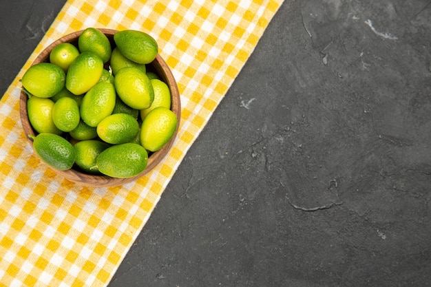 Vue en gros plan de fruits bol de fruits sur la nappe blanc-jaune sur la table sombre