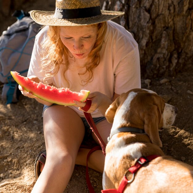 Vue de haut chien et femme mangeant une tranche de pastèque