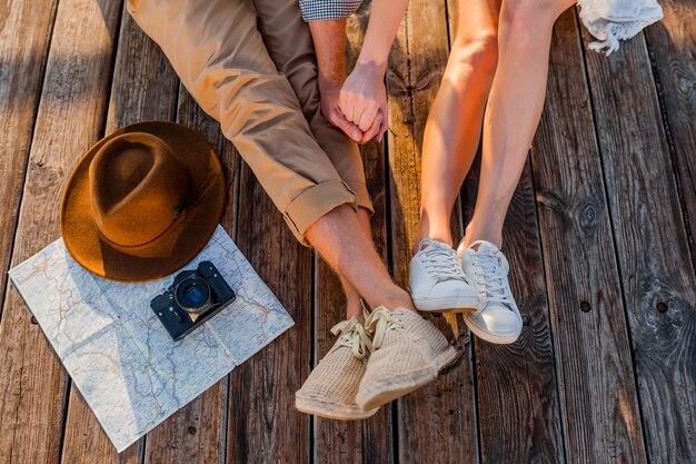 Vue d'en haut des jambes de couple voyageant en été habillé en baskets, homme et femme mode de style hipster boho s'amuser ensemble, carte, chapeau, appareil photo, tourisme, mode chaussures