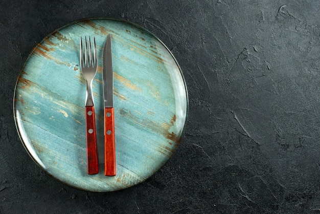 Vue horizontale des couverts de repas sur une assiette bleue sur le côté droit sur une surface sombre