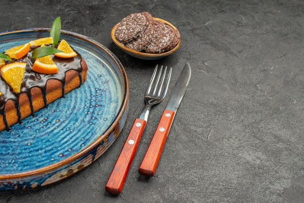 Vue horizontale de délicieux gâteaux et biscuits avec fourchette et couteau sur tableau noir
