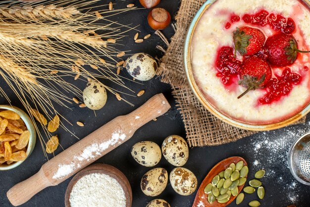 Vue horizontale d'un délicieux petit-déjeuner servi avec de la confiture de fraises dans un bol et de la farine de raisins secs jaunes sur fond de couleur sombre