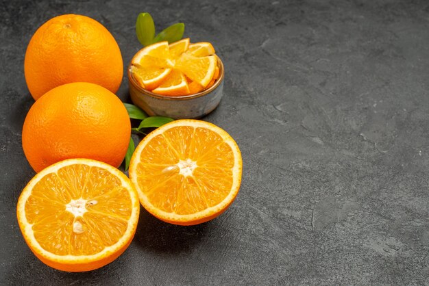 Vue horizontale de l'ensemble d'oranges jaunes entières et hachées sur table sombre