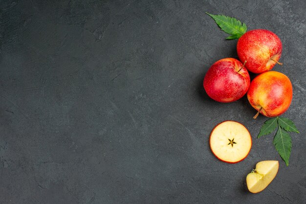 Vue horizontale de pommes rouges biologiques naturelles entières et coupées avec des feuilles vertes sur fond noir