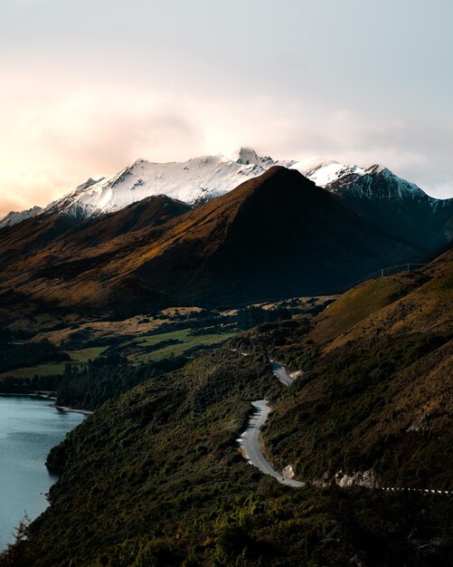 Vue imprenable sur le coucher de soleil sur le mont enneigé du lac Wakatipu et une route sur le versant de la montagne en Nouvelle-Zélande