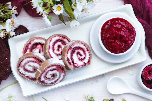 Vue imprenable sur de délicieux petits pains aux framboises et confiture de framboises mis sur plaque blanche