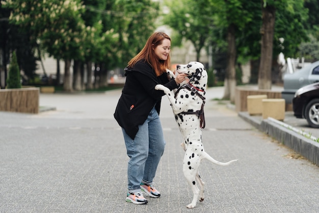 Vue de la jeune femme de race blanche jouant et entraînant son chien dalmatien