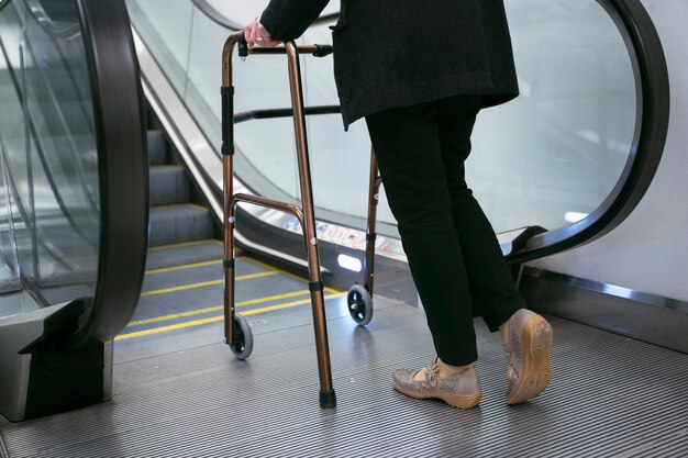 Vue latérale adulte avec déambulateur près des escalators