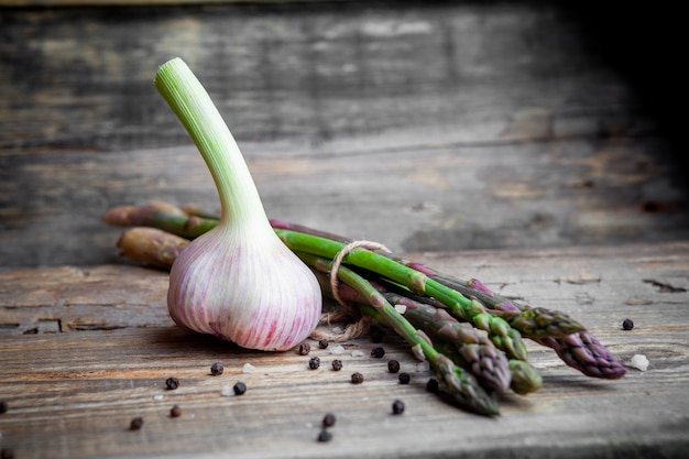 Vue latérale de l'ail avec un tas d'asperges sur fond de bois foncé. horizontal