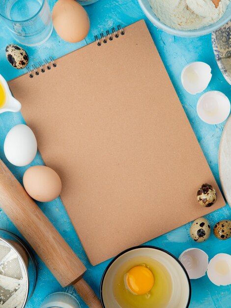 Vue latérale des aliments comme le jaune d'oeuf d'oeuf avec de l'eau et un rouleau à pâtisserie sur fond bleu avec copie espace