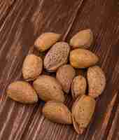 Photo gratuite vue latérale d'amandes en coquille éparpillées sur fond de bois